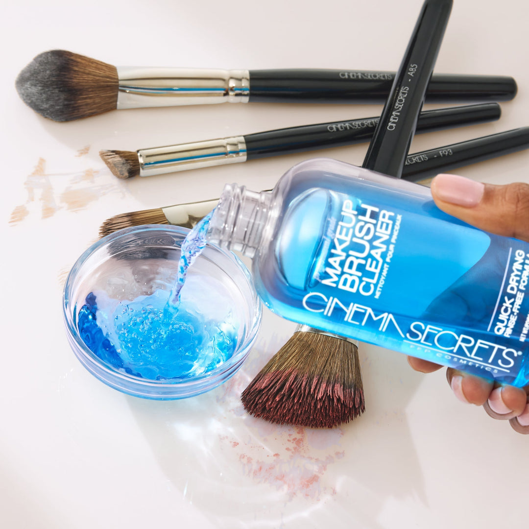 hand holding a makeup brush, cleaning makeup brushes with a blue makeup brush cleaner