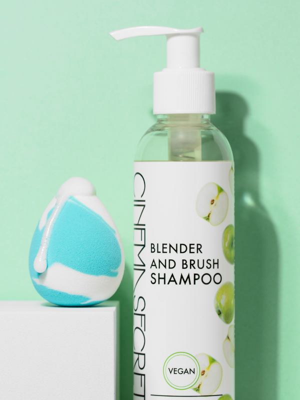 Bottle of blender and brush shampoo with a white pump on a green background