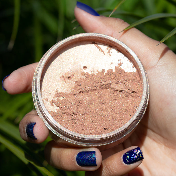 hand holding open container of highlight powder over grass