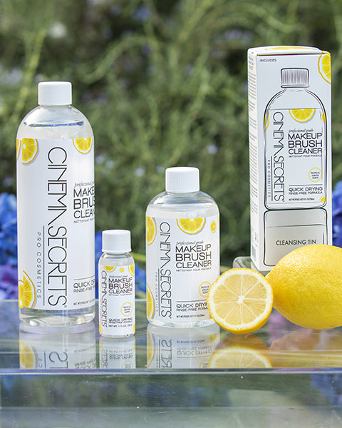 Group of brush cleaner bottles on a glass table with lemons with a forest background